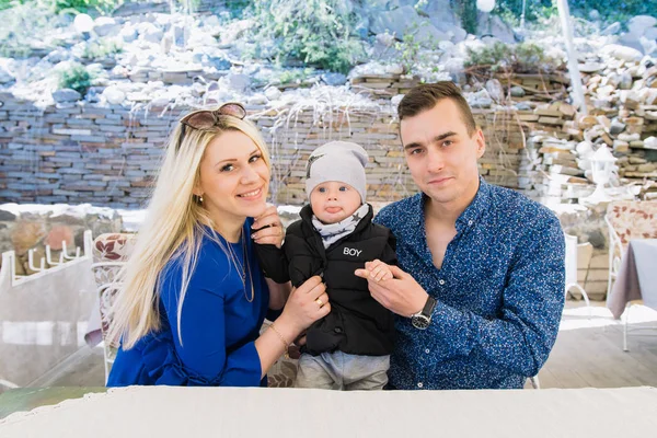 Um casal feliz está sentado em um café e aproveitando este tempo. Eles brincam com seu filho, ele sorri . — Fotografia de Stock