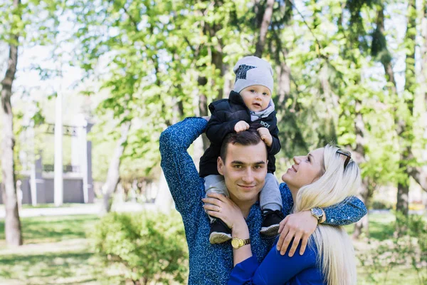 Šťastná mladá rodina tráví čas spolu venku v zelené přírodě — Stock fotografie