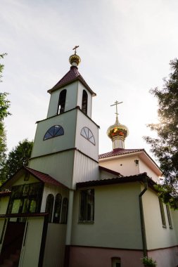 Yemyeşil ağaçlar ve mavi bulutlar arasında eski kilise.