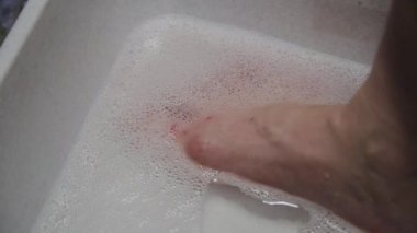 Kadın sabunlu suyla ayaklarını yıkar.