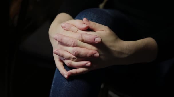 Une femme consulte son médecin en civil avant son examen. Elle porte un jean et une chemise décontractée. Gros plan de ses mains reposant sur ses genoux — Video