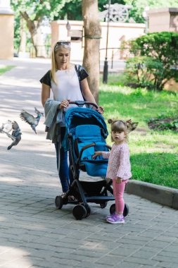 Parkta bir bebek arabası itme sırasında yürüyüş anne