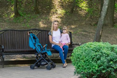 Parkta bir bebek arabası itme sırasında yürüyüş anne