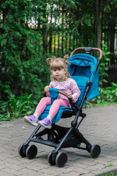 Маленькая девочка сидит в коляске в красивом парке . — стоковое фото