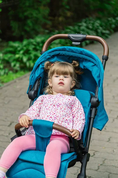 Маленькая девочка сидит в коляске в красивом парке . — стоковое фото