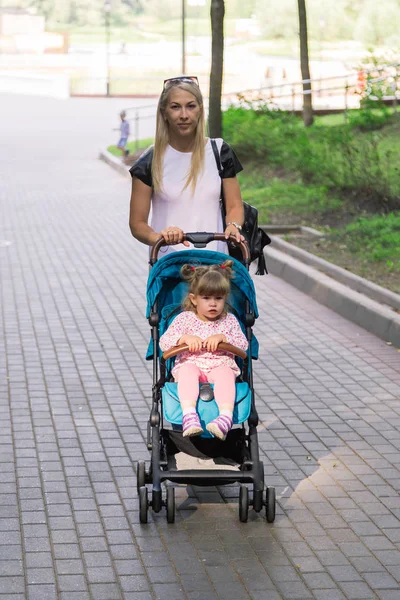Mamma che cammina spingendo un passeggino nel parco — Foto Stock