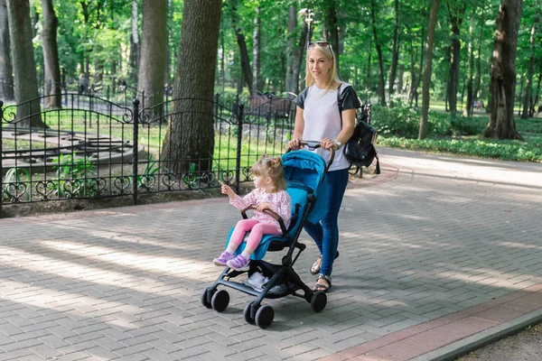 Мама гуляла, толкая коляску в парке — стоковое фото