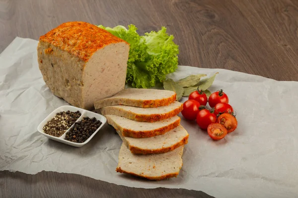 Meat product in the form of bread with spices and on baking paper.