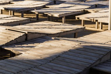 Güneşli bir sahilde ahşap şezlong