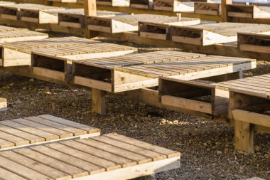 Güneşli bir sahilde ahşap şezlong.