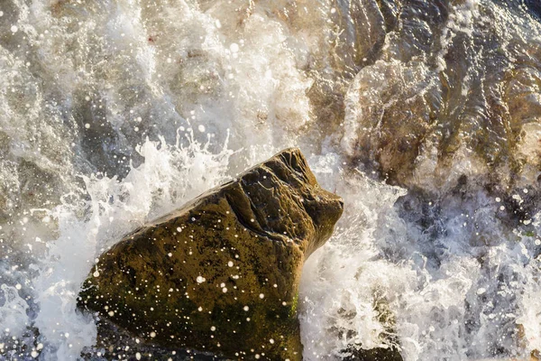 Zee golven strijden tegen de grote rotsen aan de kust. — Stockfoto