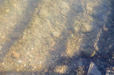 çakıl plaj çakıl deniz ve güneşin ışınları tarafından aydınlatılan su dalgaları üzerinde.