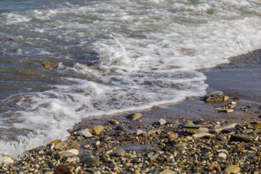 çakıl plaj çakıl deniz ve güneşin ışınları tarafından aydınlatılan su dalgaları üzerinde.