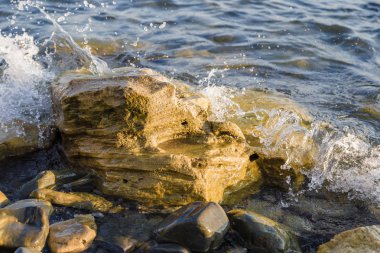 Dalgalar deniz kıyısında büyük kayalara karşı mücadele ediyoruz.