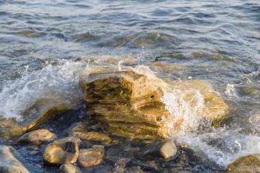 Dalgalar deniz kıyısında büyük kayalara karşı mücadele ediyoruz.