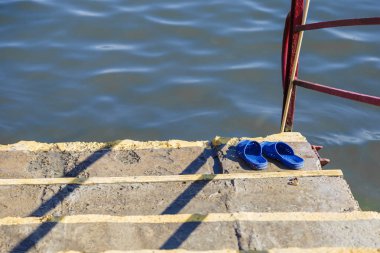 Nehri yakınında ahşap döşeme üzerinde duruyor Ayakkabı Yaz: flip flop..