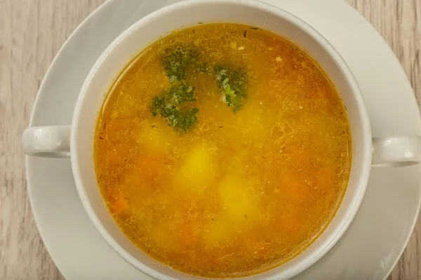 Placa con sopa en un plato blanco sobre un fondo de madera . — Foto de Stock