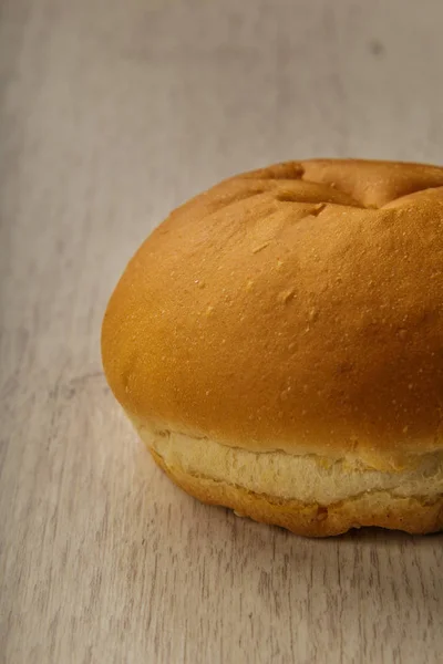 Fresh ruddy bun on a wooden background. — Stock Photo, Image