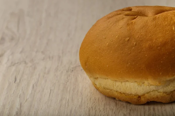 Fresh ruddy bun on a wooden background. — Stock Photo, Image