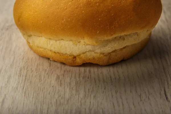 Fresh ruddy bun on a wooden background. — Stock Photo, Image