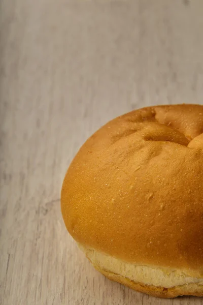 Fresh ruddy bun on a wooden background. — Stock Photo, Image