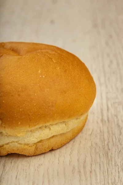 Fresh ruddy bun on a wooden background. — Stock Photo, Image