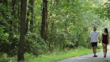 Aşık parkta elele parlak güneşli bir günde yürümek..