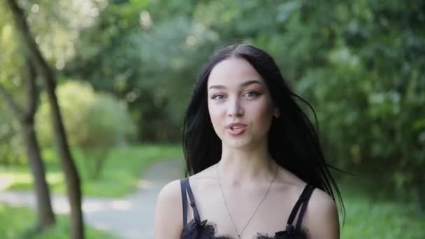 Vacker flicka pratar på kameran i en vacker park. — Stockvideo