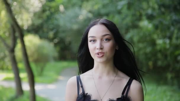 Menina bonita está falando na câmera em um belo parque . — Vídeo de Stock