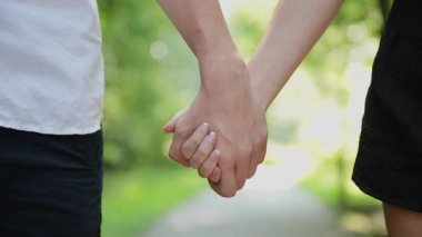 Bir çift kot giyen aşıkların elele ve birlikte, yakın çekim yürümek.