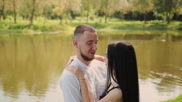 Los amantes de pie en la orilla del lago hablando abrazo y beso . — Vídeos de Stock