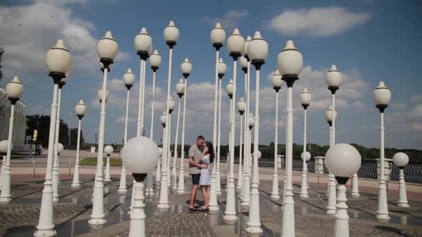 A loving couple hugs and kisses on the embankment near the street lamps. — Stock Video