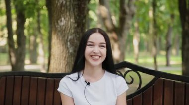 Güzel kız kameranın güzel bir parkta konuşuyor.