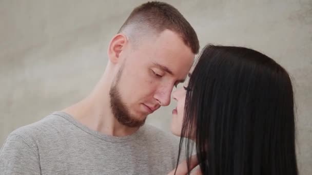 A loving couple hugs and kisses against the background of a concrete wall. — Stock Video