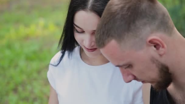 Due amanti si siedono su una panchina e si sorridono guardando le foto di famiglia . — Video Stock