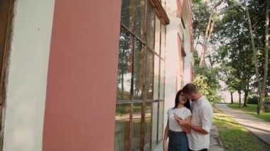 Sevgi dolu birkaç hugs ve parkta büyük pencereler ile bir bina yakınındaki kisses.