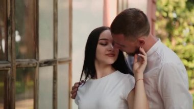 Sevgi dolu birkaç hugs ve parkta büyük pencereler ile bir bina yakınındaki kisses.