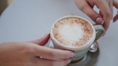 Güzel bir kızın elinde kapuçino.