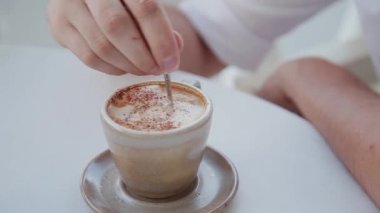 Bir adam bir fincan taze yapılmış kapuçino tutuyor.