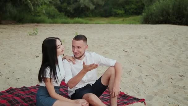 Αγάπη ζευγάρι κάθεται στην παραλία και αγκαλιάζει, ηλιοβασίλεμα. — Αρχείο Βίντεο