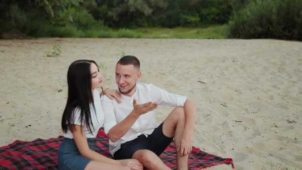 Pareja cariñosa sentada en la playa y abrazándose, puesta de sol . — Vídeo de stock