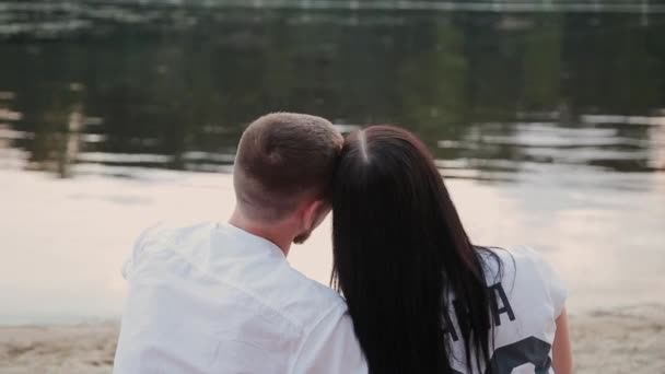 Pareja cariñosa sentada en la playa y abrazándose, puesta de sol . — Vídeos de Stock