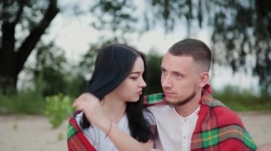 Sevgi dolu çift oturma plaj ve sarılma, günbatımı üzerinde.