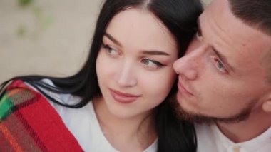 Sevgi dolu çift oturma plaj ve sarılma, günbatımı üzerinde.