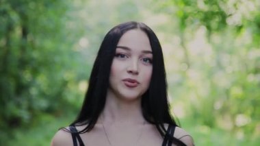 Güzel kız kameranın güzel bir parkta konuşuyor.