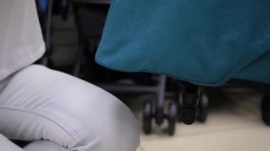 Kamera bir çocuk deposundaki bir bebek arabası katlama işlemi.