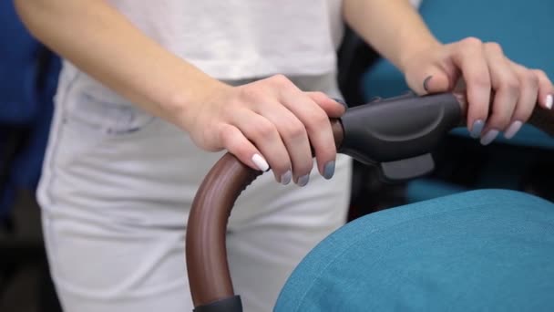 A woman is holding a baby carriage by her hands, close-up. — Stock Video