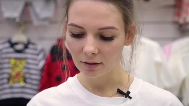 Una chica muy hermosa lee un texto de una hoja en una tienda para niños . — Vídeo de stock