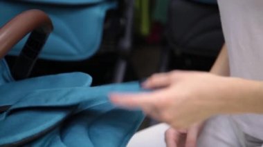 Kamera bir çocuk deposundaki bir bebek arabası katlama işlemi.