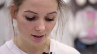 Çok güzel bir kız bir metin bir yaprak bir mağazada çocuklar için okur.